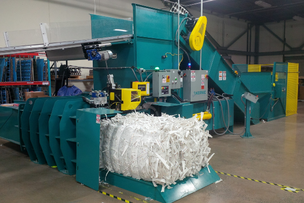 large blue two ram baler with shredded paper bale