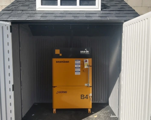 small yellow baler in outdoor shed