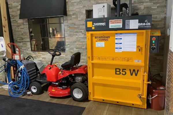 yellow vertical baler next to red lawn mower