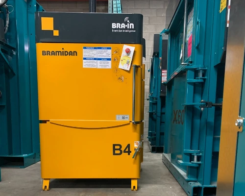 small yellow baler in warehouse next to large teal balers