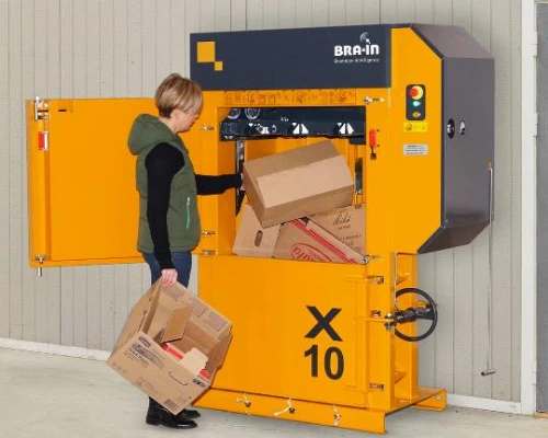 woman filling a yellow baler with cardboard