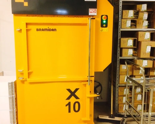 yellow x10 baler under low ceiling next to warehouse rack