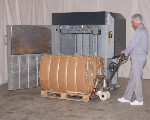 man pulling an ejected cardboard bale on a pallet from a galvanized finish baler