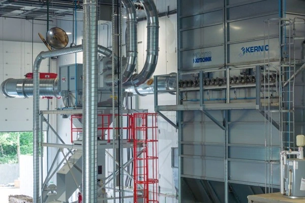 Industrial mechanical room with large silver ductwork and piping, red safety ladder, and wall-mounted equipment for dust collecting
