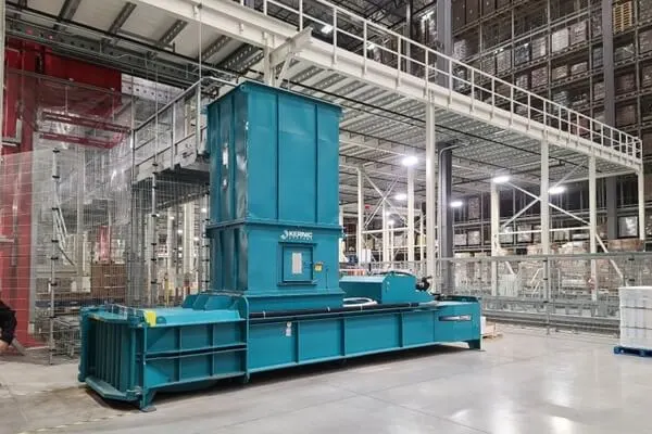 Large blue industrial machine in a spacious factory, with metal catwalks and overhead infrastructure in the background.